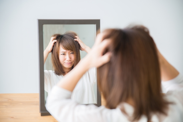 白髪が出てきて悲しんでいる女性の画像